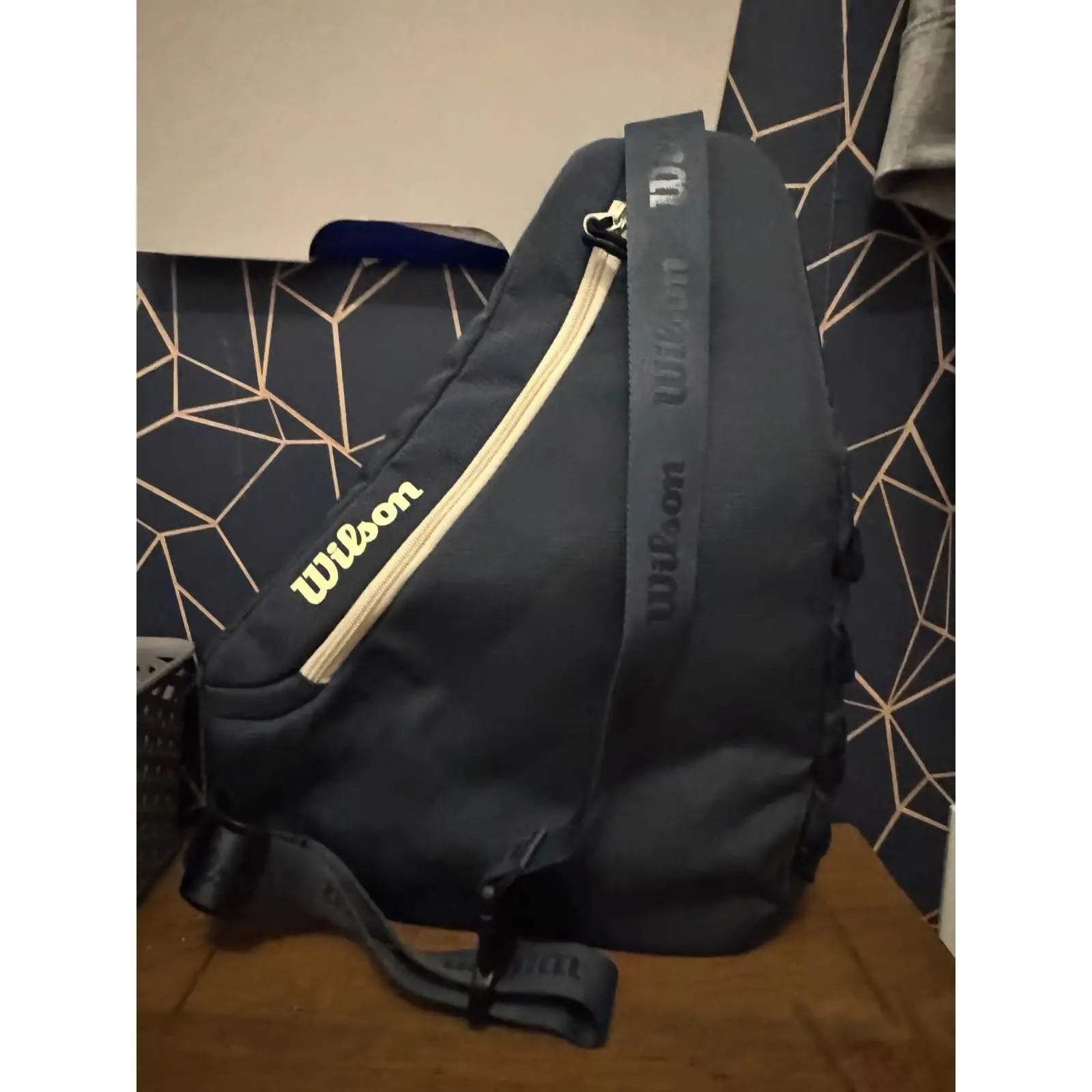 Dark blue Wilson Triangle Pickleball Sling Bag with a light yellow zipper and logo, showcasing its compact design.