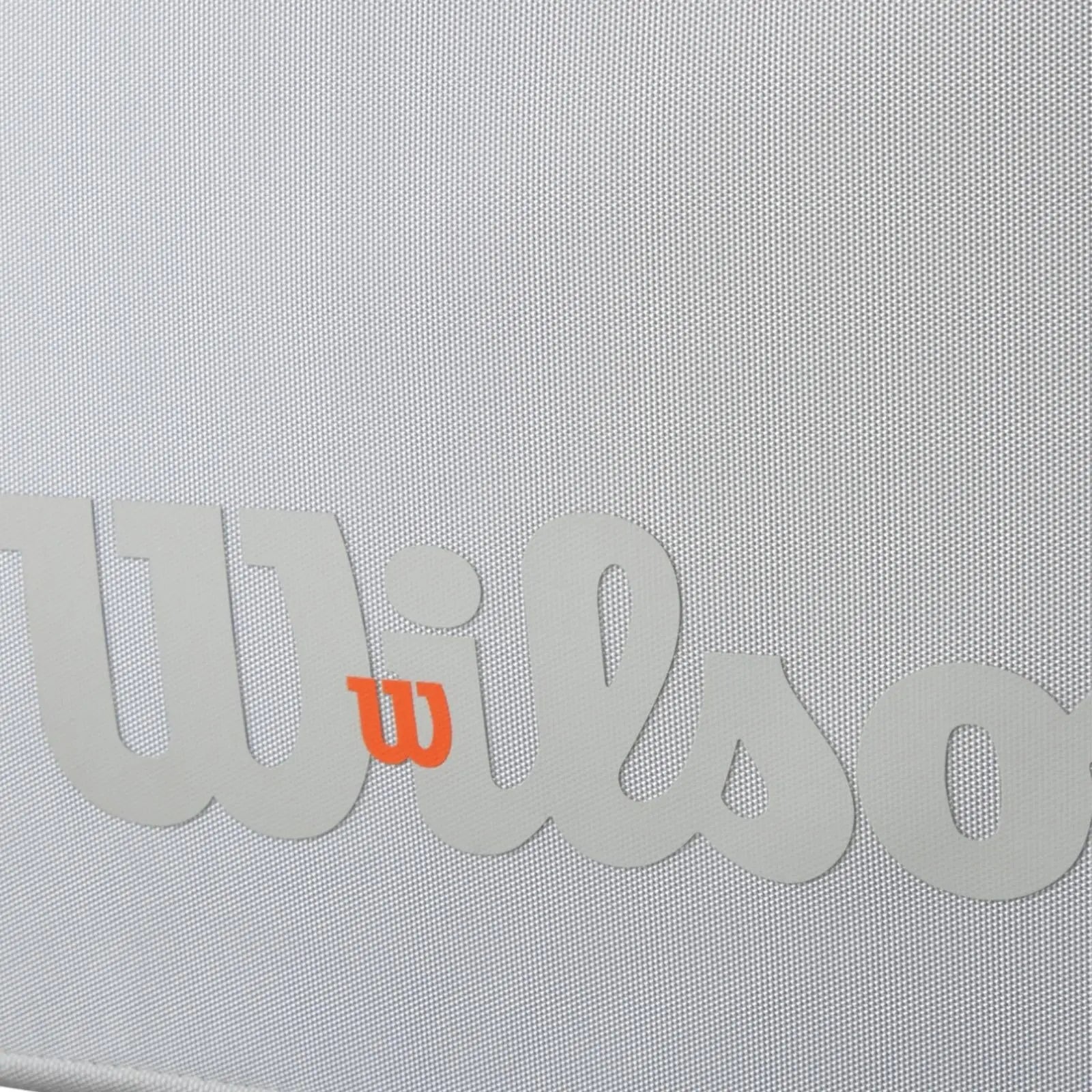 Close-up of a white Wilson tennis bag with a textured surface and a gray Wilson logo, featuring an orange "W".