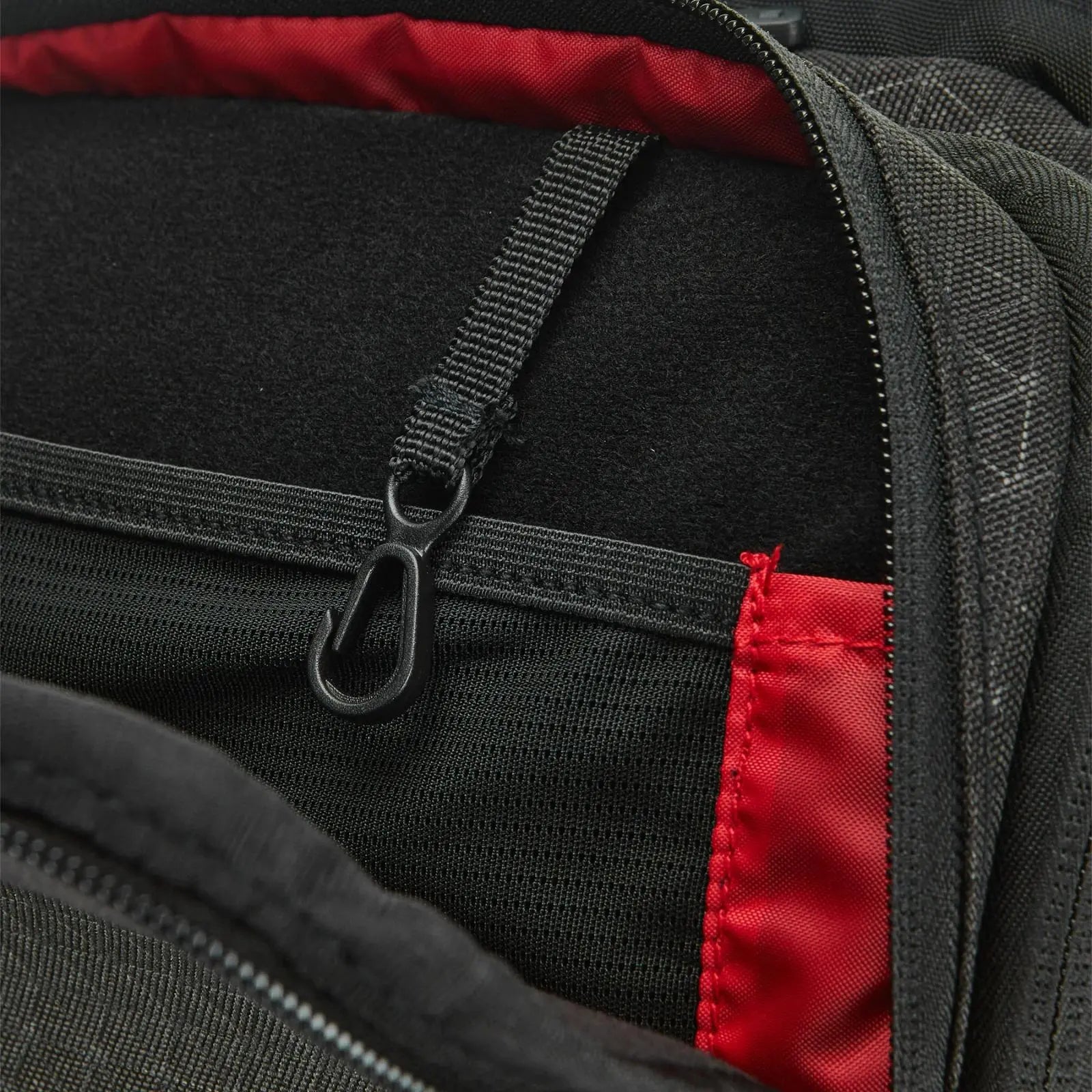 Close-up of the black Wilson Super Tour Clash v3 Tennis Backpack's interior, showing a black hook and red lining.