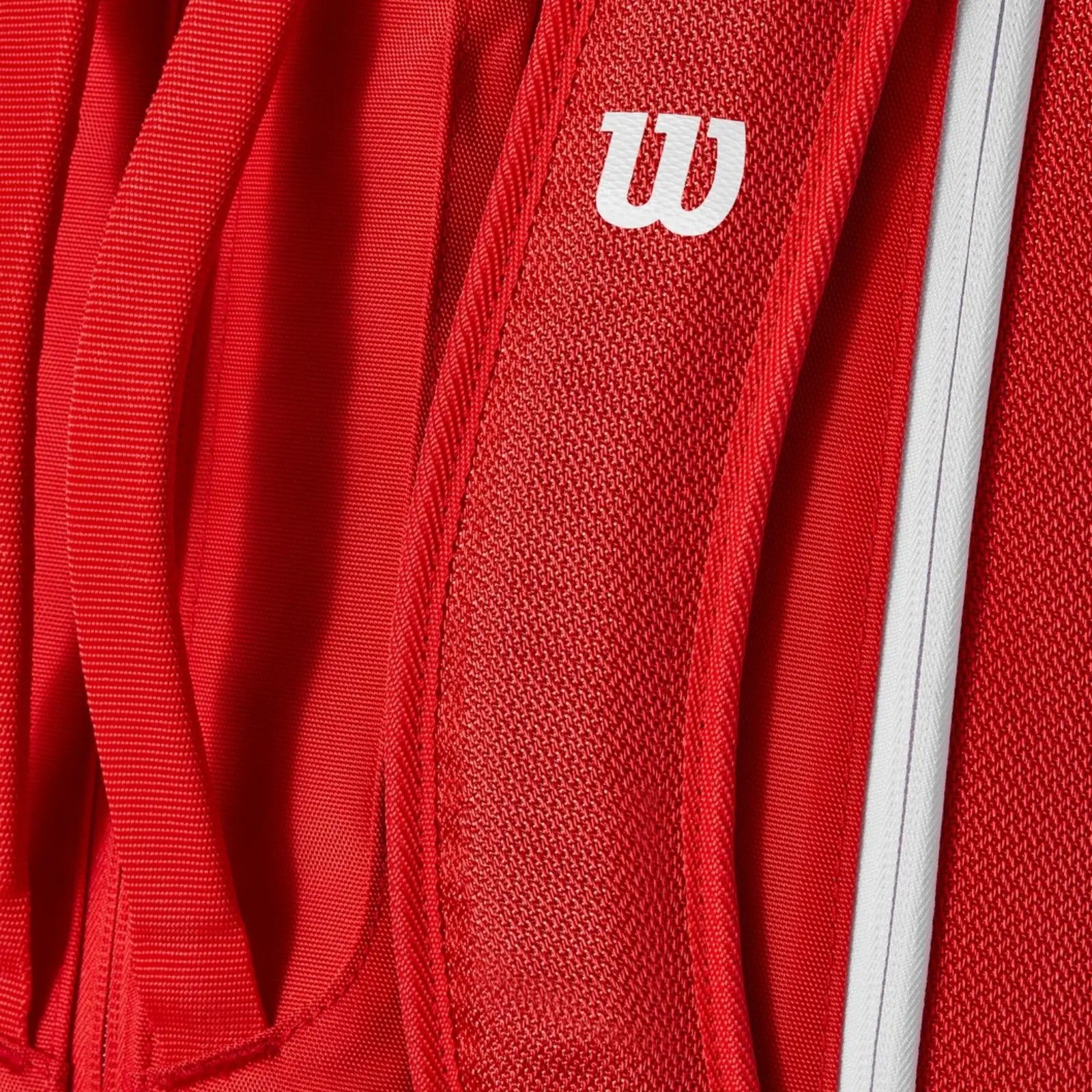 Close-up of a red Wilson Super Tour tennis bag, showing the white Wilson logo and textured fabric.