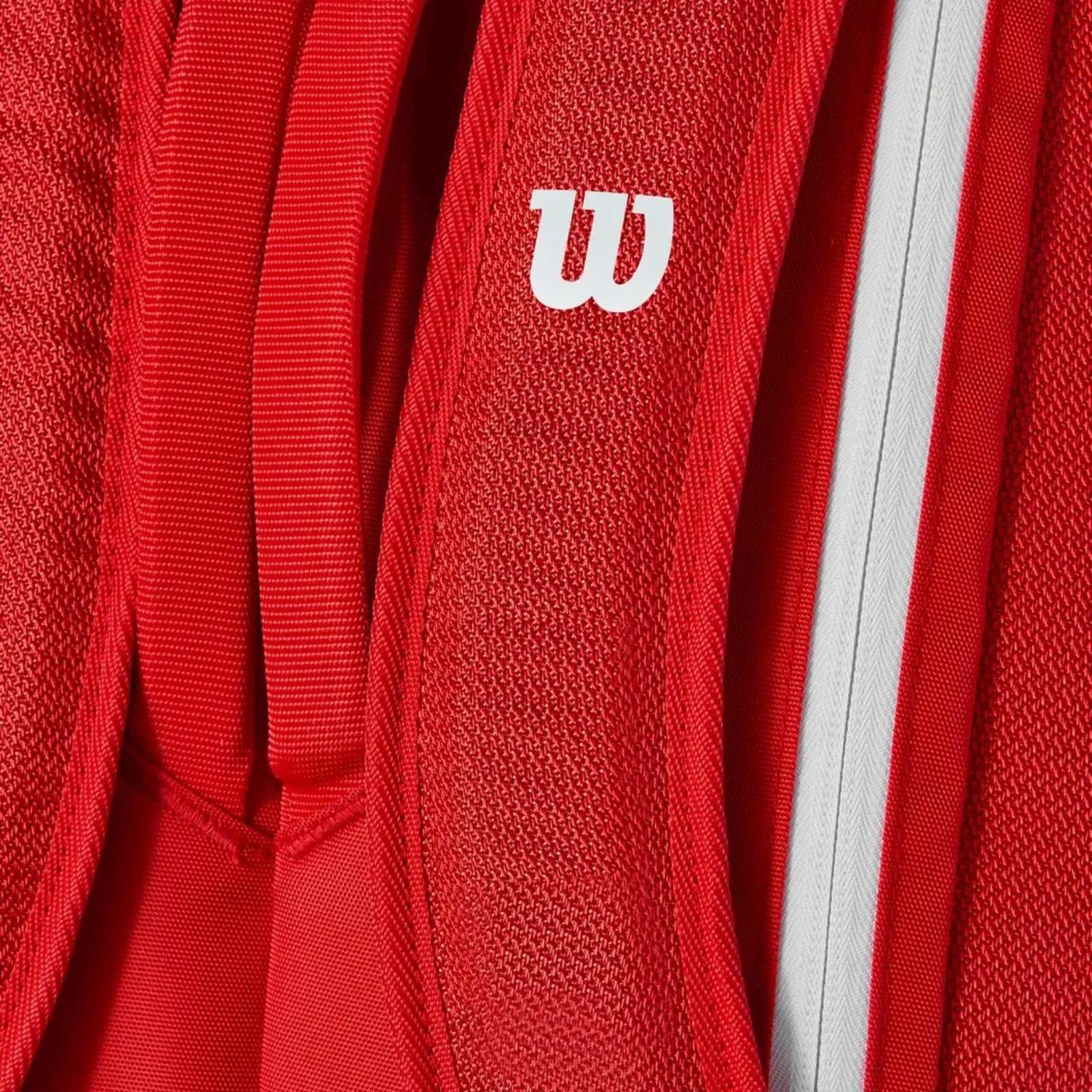 Close-up of a vibrant red Wilson Super Tour tennis bag with a white logo and zipper detail.