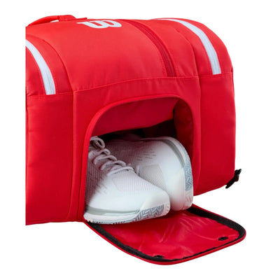 Red Wilson Super Tour pickleball bag with a dedicated shoe compartment holding white athletic shoes.