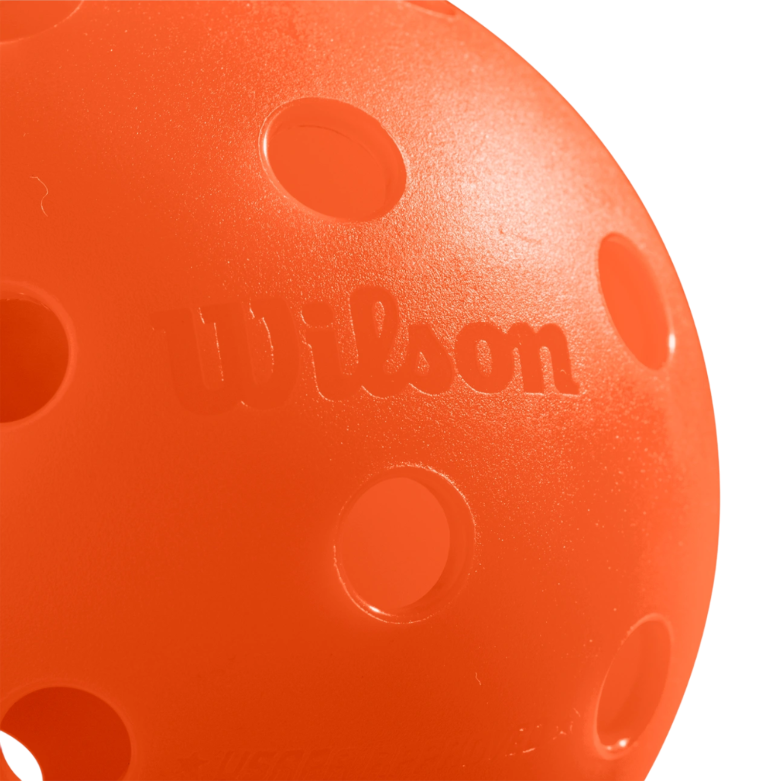 Close-up of a bright orange Wilson Tru 32 indoor pickleball with visible 32-hole design and rough finish.