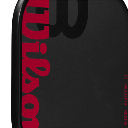 Close-up of a black Wilson Blaze Pro 13 pickleball paddle with red "Wilson" logo and "Blaze Pro 13" text.