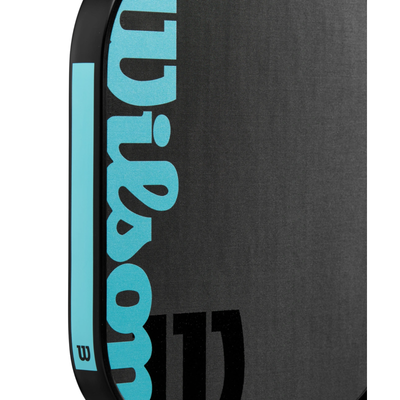 Close-up of the black Wilson Cadence 16mm Pickleball Paddle with a blue Wilson logo and raw carbon face.