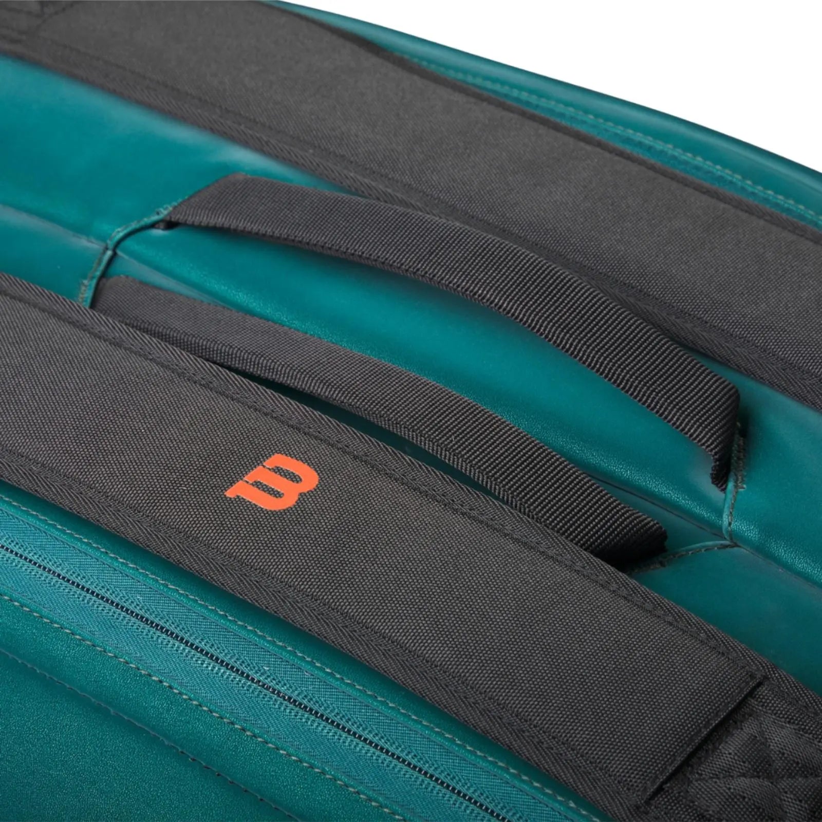 Close-up of a Wilson Blade Super Tour 9 tennis bag in emerald green with black padded straps and an orange "W" logo.