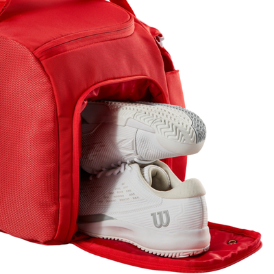 Red Wilson Super Tour Small Duffle tennis bag with white tennis shoes in the dedicated shoe compartment.