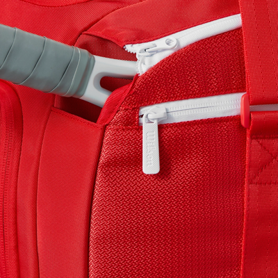 Red Wilson Super Tour Small Duffle tennis bag with a racket handle in a zippered compartment.