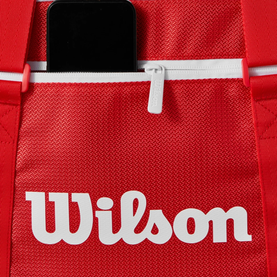 Red Wilson Super Tour small duffel bag with white logo, zipper, and phone in an accessory pocket.