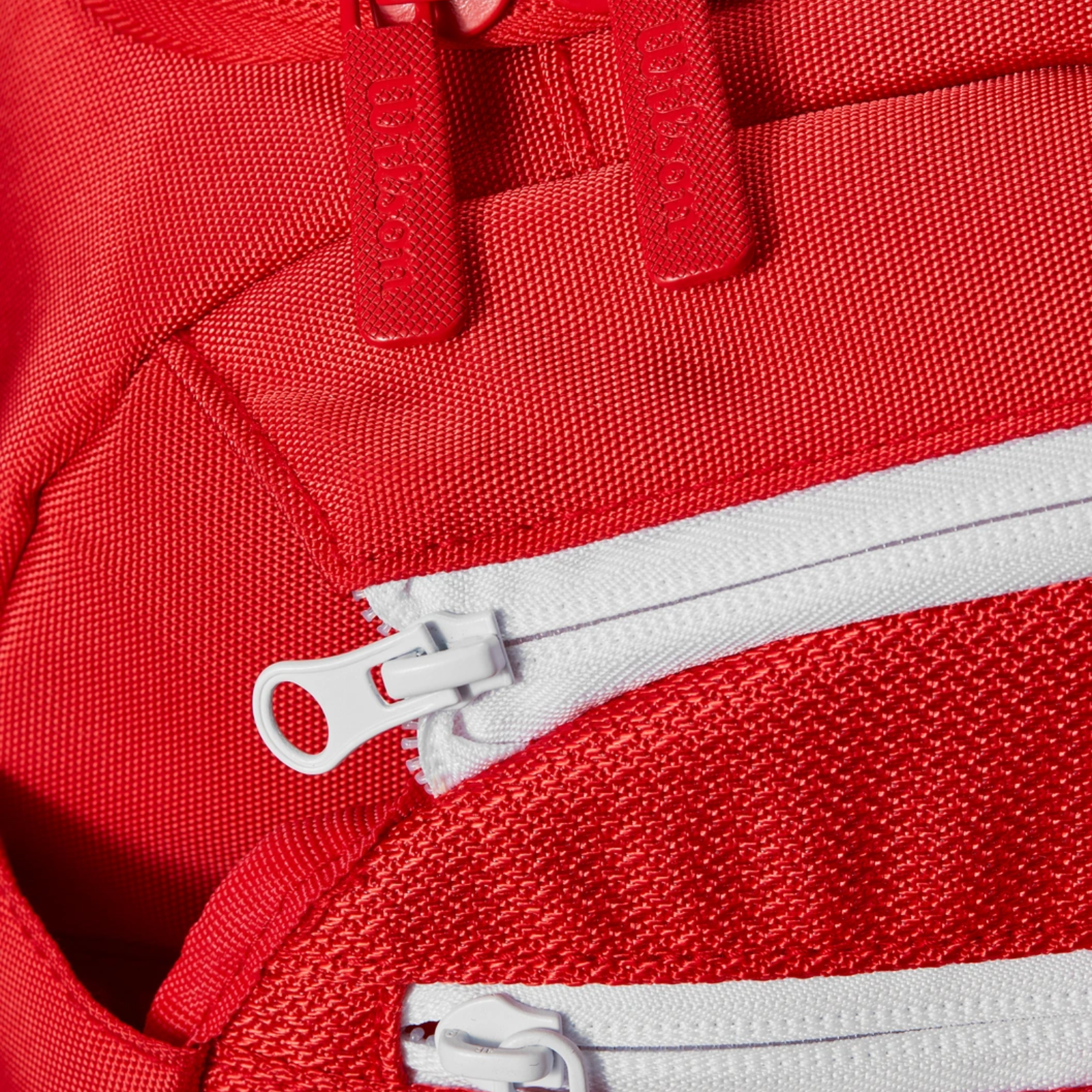 Close-up of a red Wilson Super Tour Small Duffle tennis bag with white and red zippers.