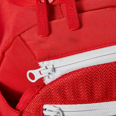 Close-up of a red Wilson Super Tour Small Duffle tennis bag with white and red zippers.