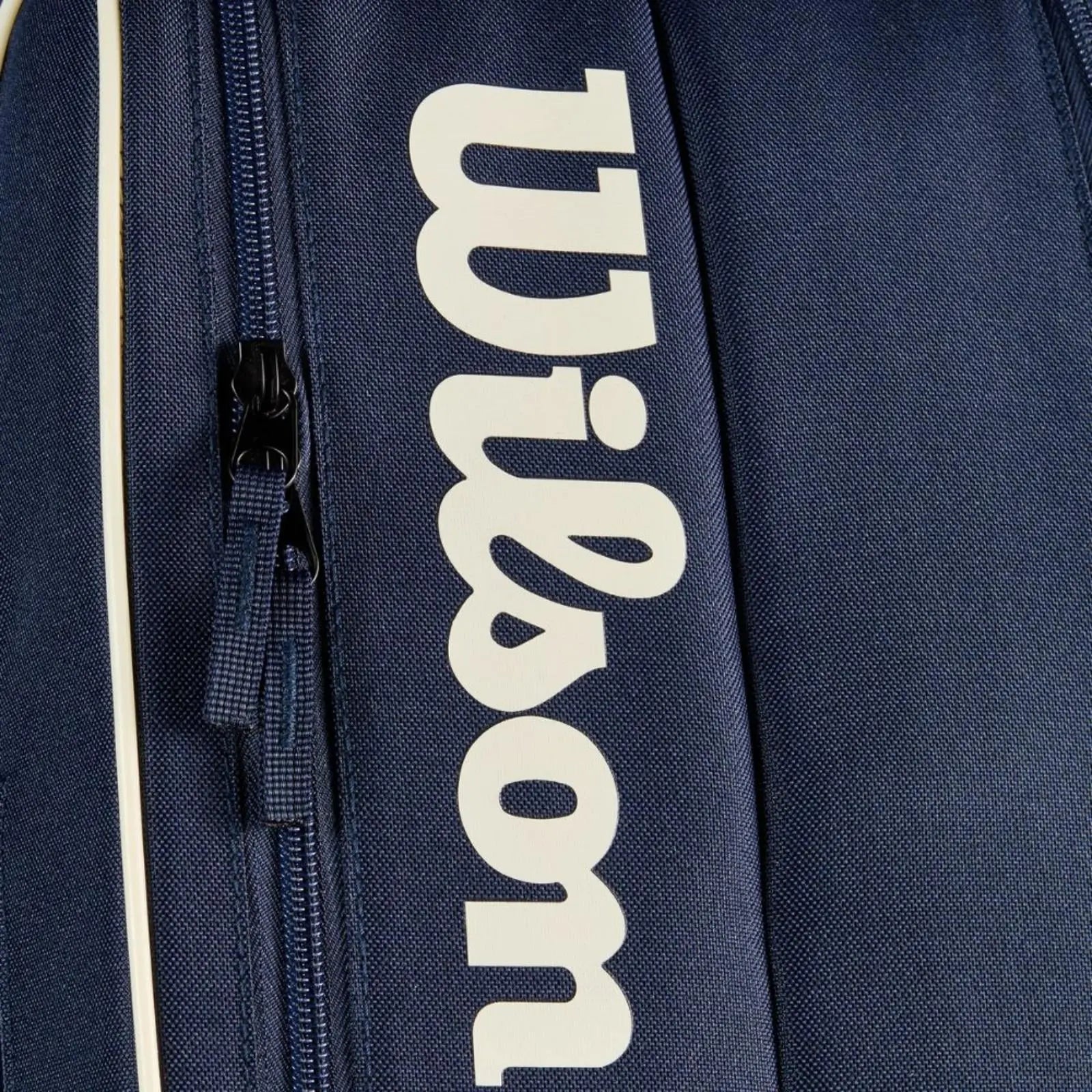 Close-up of a navy Wilson Team 6 Pack tennis bag with white logo, zipper, and light trim.